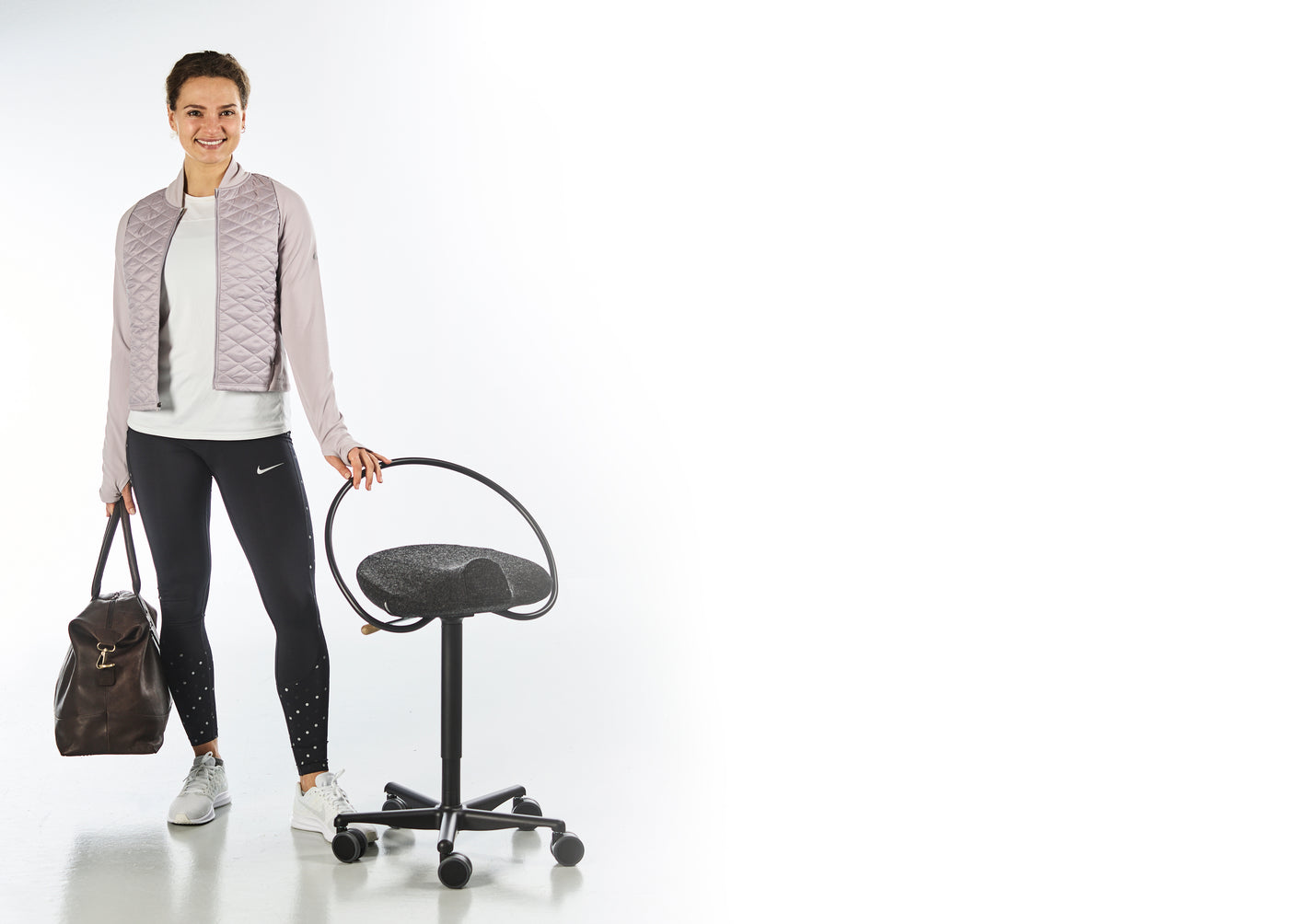 Aktiv kvinna står med en sportväska i ena handen och en svart InCharge Office klädd i svart Hallingdalsull från Kvadrat.